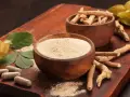 Radici, polvere e capsule di ashwagandha su tagliere di legno. Scopri come assumere ashwagandha per il benessere.
