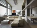 Un ampio soggiorno moderno, perfetto per arredare soggiorno grande, con divano componibile in pelle chiara, tavolino squadrato e zona pranzo con tavolo lungo e sedie di design.