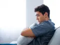Ragazzo pensieroso abbraccia un cuscino, riflettendo sull'insonnia adolescenza rimedi naturali.