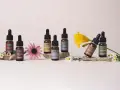 Flaconi di Fiori di Bach Rescue Remedy con Mimulus, Chicory, Wild Rose, Star of Bethlehem, Holly, Scleranthus e Impatiens, circondati da fiori.