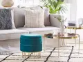 Pouf fai da te turchese in velluto, con gambe dorate, accanto a un divano e tavolini in un soggiorno moderno.