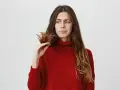 Donna preoccupata guarda le doppie punte, pensando a come nutrire i capelli per renderli sani e forti.