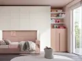 Camera ragazza aesthetic con letto rosa, armadio bianco e rosa, libreria con libri e decorazioni, pouf e grande finestra.