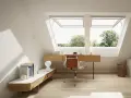 Accogliente mansarda studio con scrivania in legno, sedia in pelle e ampie finestre sul tetto che offrono una vista sul verde.