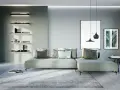 Soggiorno di una casa moderna con divano angolare, quadri e mensole illuminate.