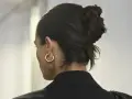 Capelli scuri raccolti in un chignon semplice, con un orecchino a cerchio dorato.