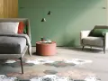 Camera da letto con pareti verde foresta, letto comodo, poltrona e un tappeto esagonale decorato.