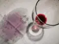 Un bicchiere di vino rosso rovesciato ha lasciato delle macchie sul tovagliolo, creando un'atmosfera di festa finita.