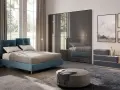 Un letto blu moderno, un armadio a specchio e quadri paesaggistici creano camere da letto da sogno.