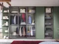 Stanza con armadi chiusi in vetro, ordinati con abiti appesi e scatole contenitive.
