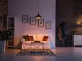 Un divano bianco accogliente, con cuscini colorati, in un soggiorno con mattoni a vista e quadri botanici. Atmosfera di puro stile cozy.