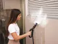 Donna usa un pulitore a vapore per pulire una superficie, come se stesse per pulire moquette con vaporetto.