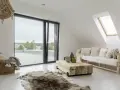 Un salotto con un divano bianco, tavolino in legno grezzo e tappeto in pelliccia, in un accogliente stile boho chic casa.