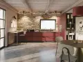 Cucina moderna con mobili rossi a vista, parete in pietra e un'isola che offre idee cucine ad angolo. Tavolo rotondo e sedie completano l'ambiente.