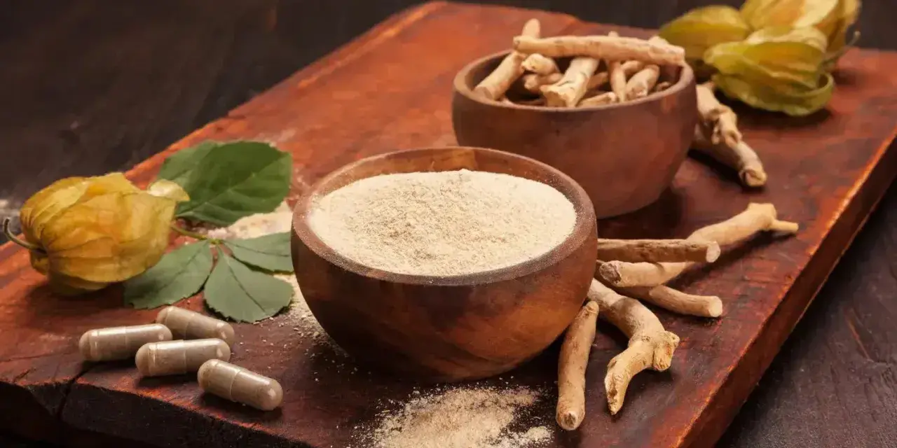 Radici, polvere e capsule di ashwagandha su tagliere di legno. Scopri come assumere ashwagandha per il benessere.