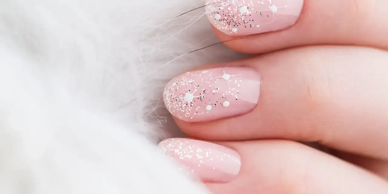 Unghie natalizie rosa pastello con brillantini scintillanti e decorazioni a stella, su sfondo bianco soffice.