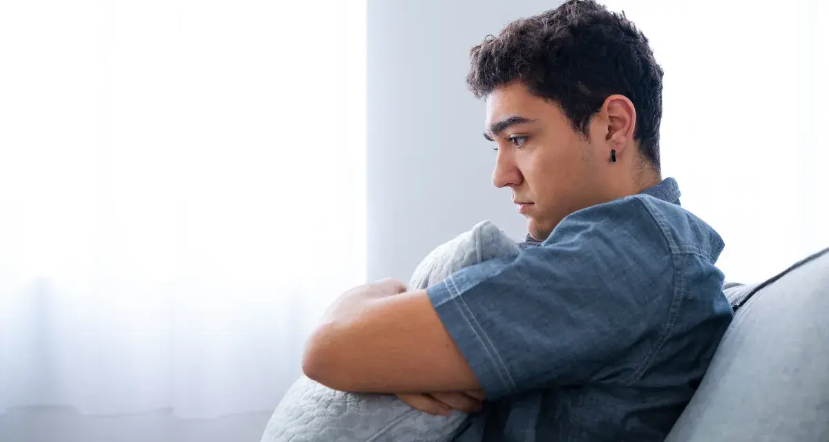 Ragazzo pensieroso abbraccia un cuscino, riflettendo sull'insonnia adolescenza rimedi naturali.