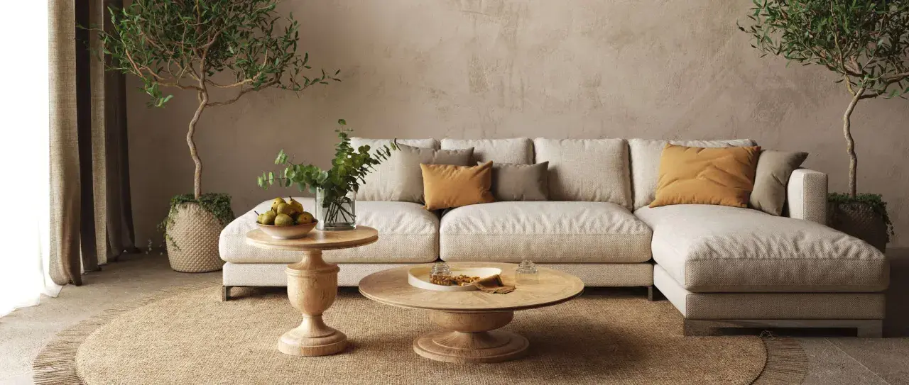 Soggiorno beige e bianco con divano modulare, tavolini in legno, piante e tappeto in juta.