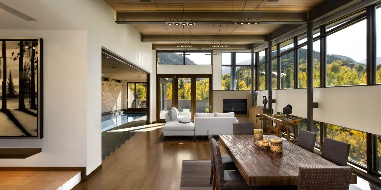 Ampio soggiorno con piscina interna, camino, tavolo da pranzo in legno e vista panoramica. Un perfetto test stile arredamento moderno.