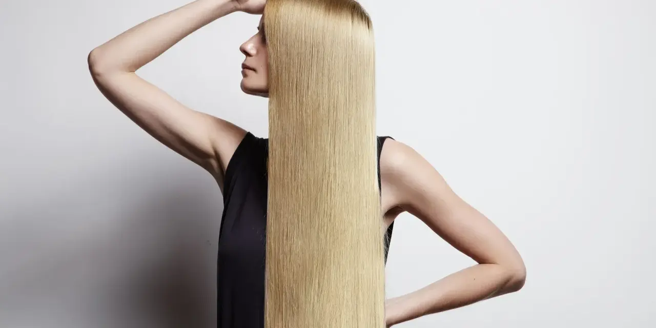 Donna con lunghi capelli biondi lisci, che mostra come lisciare i capelli a casa per un look impeccabile.
