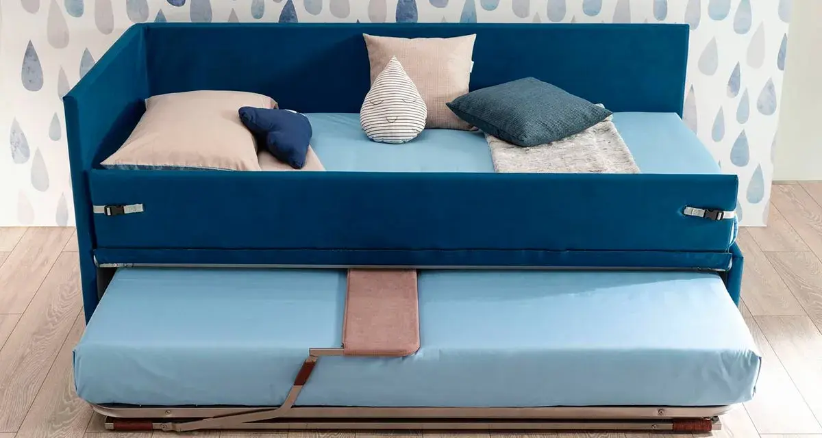 Camera studio con divano letto blu, con un secondo letto estraibile sotto. Perfetto per ospitare amici o per un riposino.