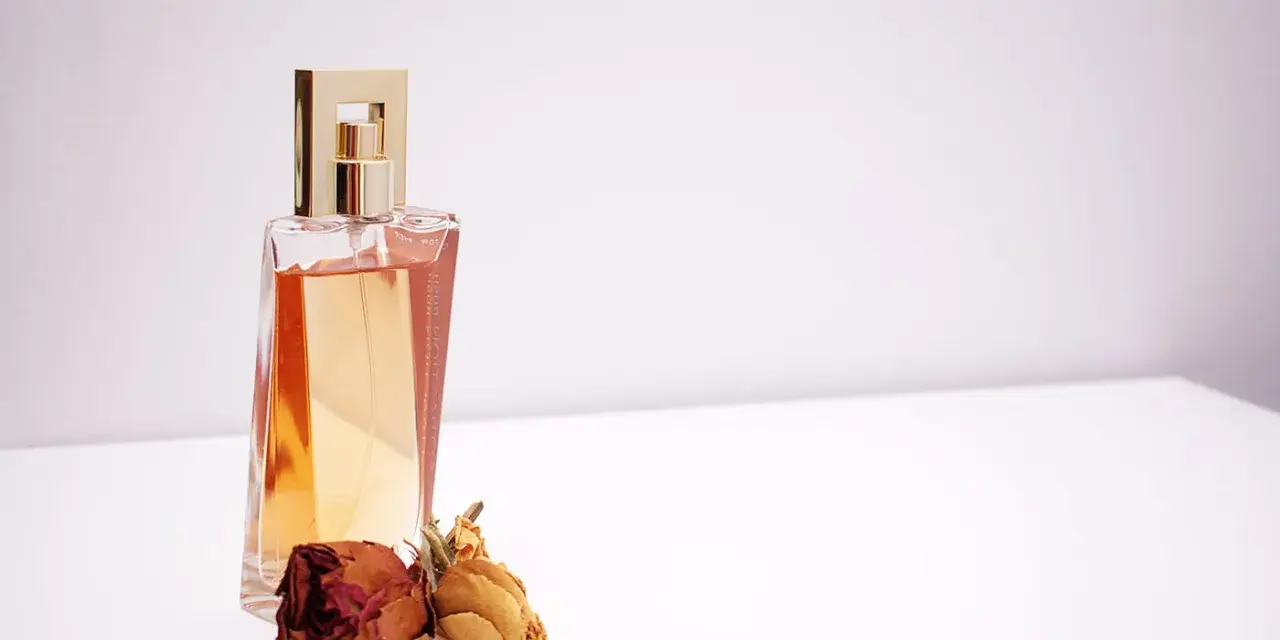 Elegante flacone di profumo dorato con rose secche, un'ispirazione su come scegliere un profumo che ti rappresenti.