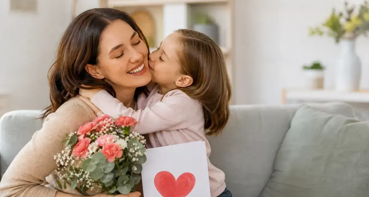 Bambina bacia la mamma, regalandole fiori e un disegno a forma di cuore. Un dolce momento per la festa della mamma.