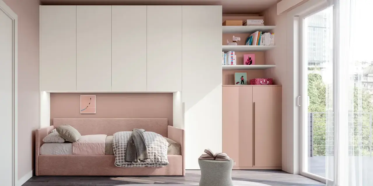 Camera ragazza aesthetic con letto rosa, armadio bianco e rosa, libreria con libri e decorazioni, pouf e grande finestra.