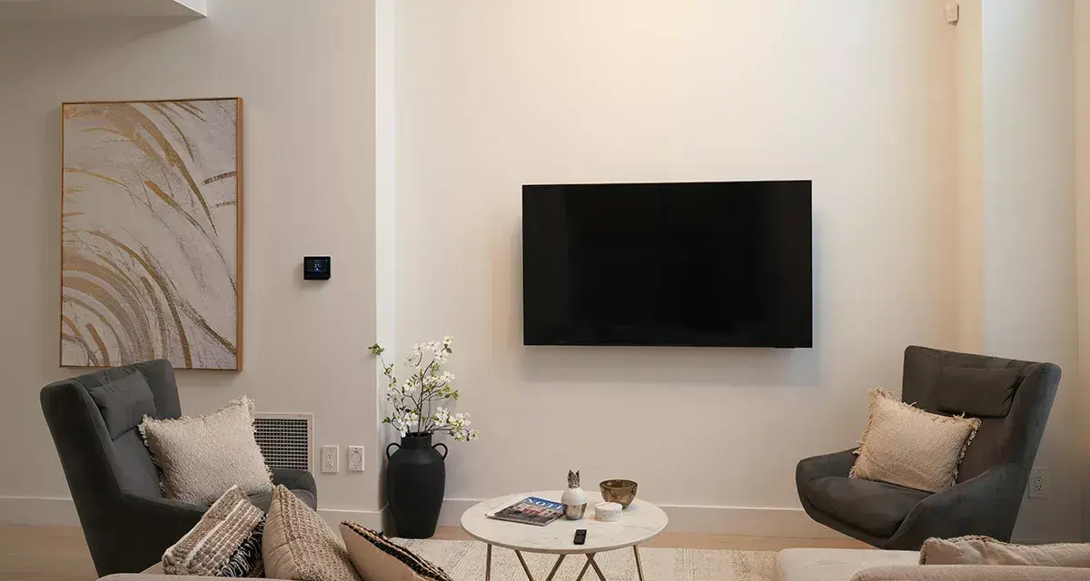 Soggiorno con TV a parete, divano, poltrone e tavolino. L'arredamento minimalista crea un'atmosfera rilassante.