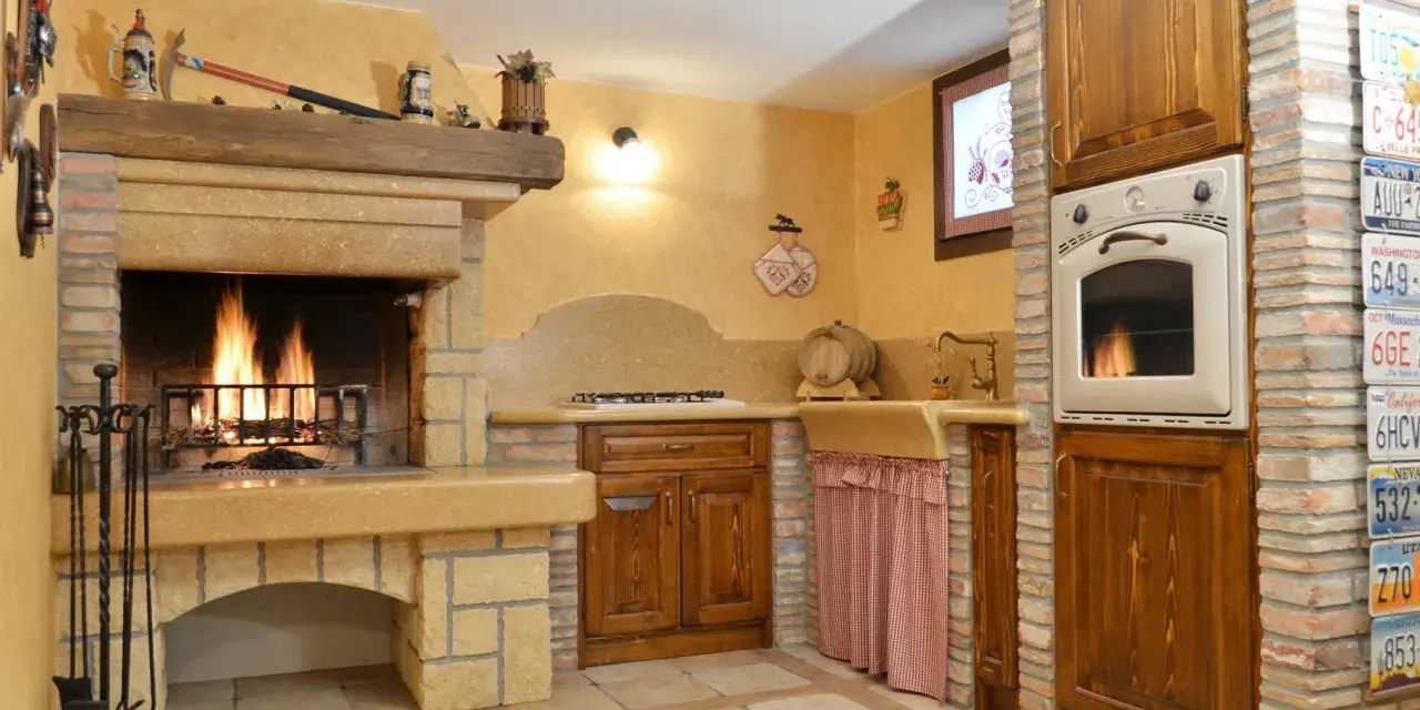 Accoglienti cucine di campagna con camino acceso, mobili in legno scuro e dettagli rustici. Un angolo cottura funzionale e un'atmosfera calda e invitante.
