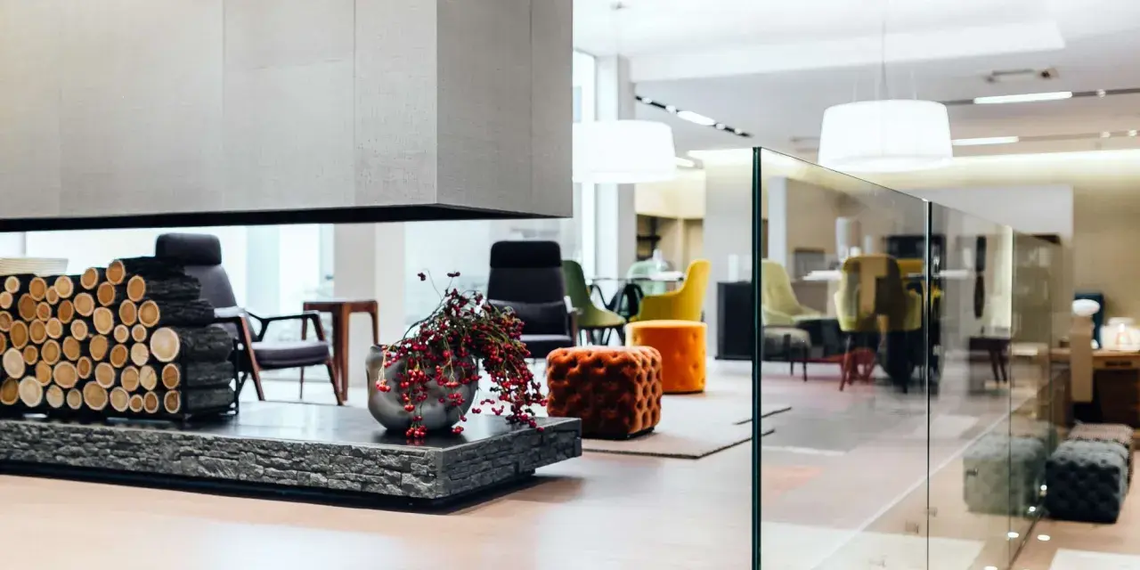Interni open space di case moderne: camino con legna, vasi con bacche rosse, sedie colorate e pouf arancioni in un ambiente luminoso.