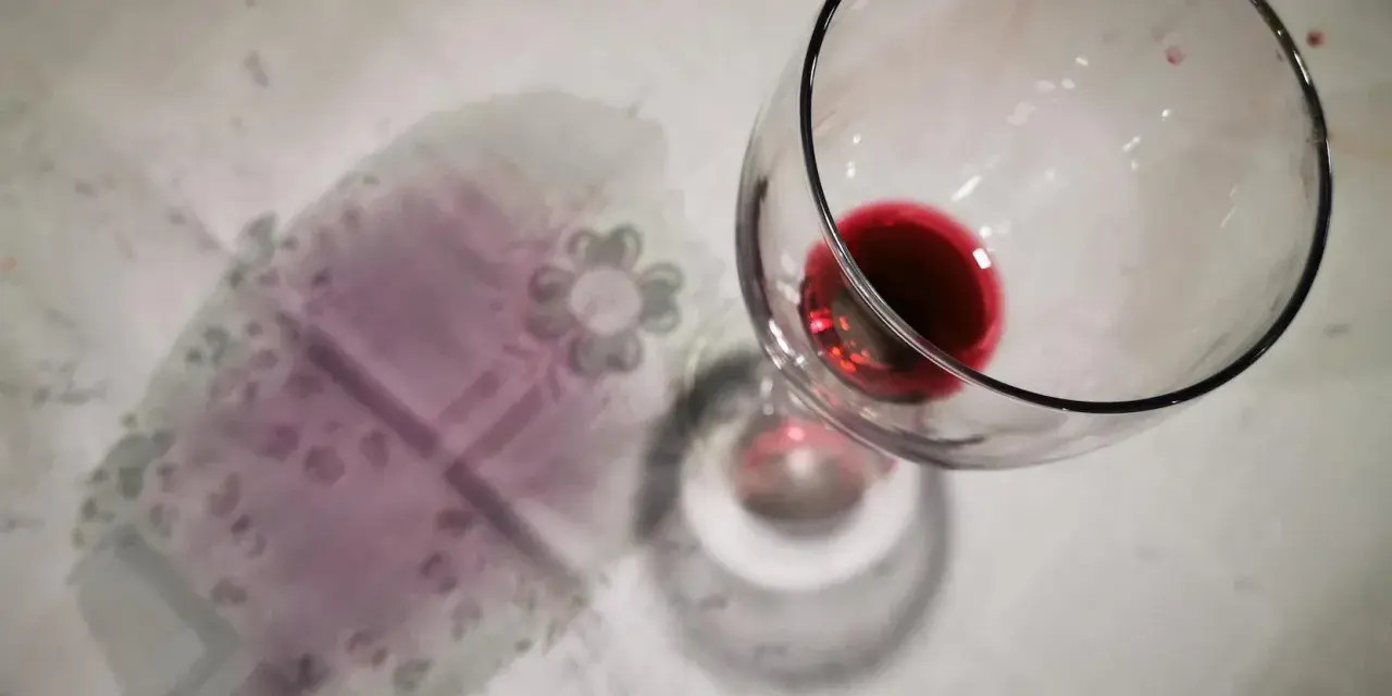 Un bicchiere di vino rosso rovesciato ha lasciato delle macchie sul tovagliolo, creando un'atmosfera di festa finita.