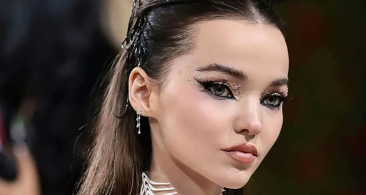 Occhi da sirena scintillanti con strass e eyeliner drammatico, capelli raccolti con accessori metallici.