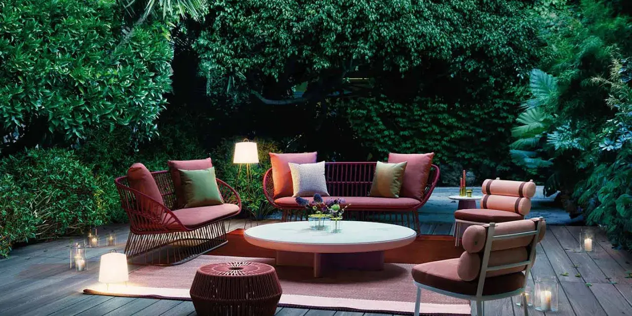 Un terrazzo accogliente con mobili da esterno color corallo e illuminazione soffusa, ideale per godersi la sera.