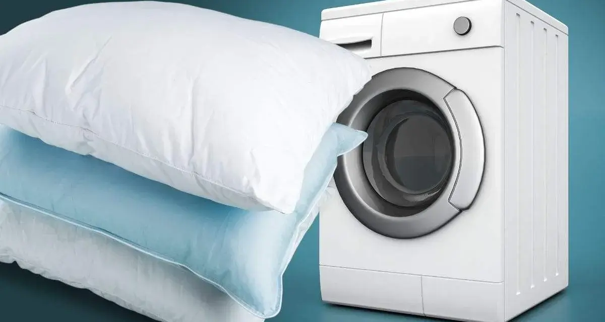 Impara come lavare i cuscini in lavatrice per un sonno fresco e igienico. Cuscini bianchi e azzurri accanto a una lavatrice bianca.