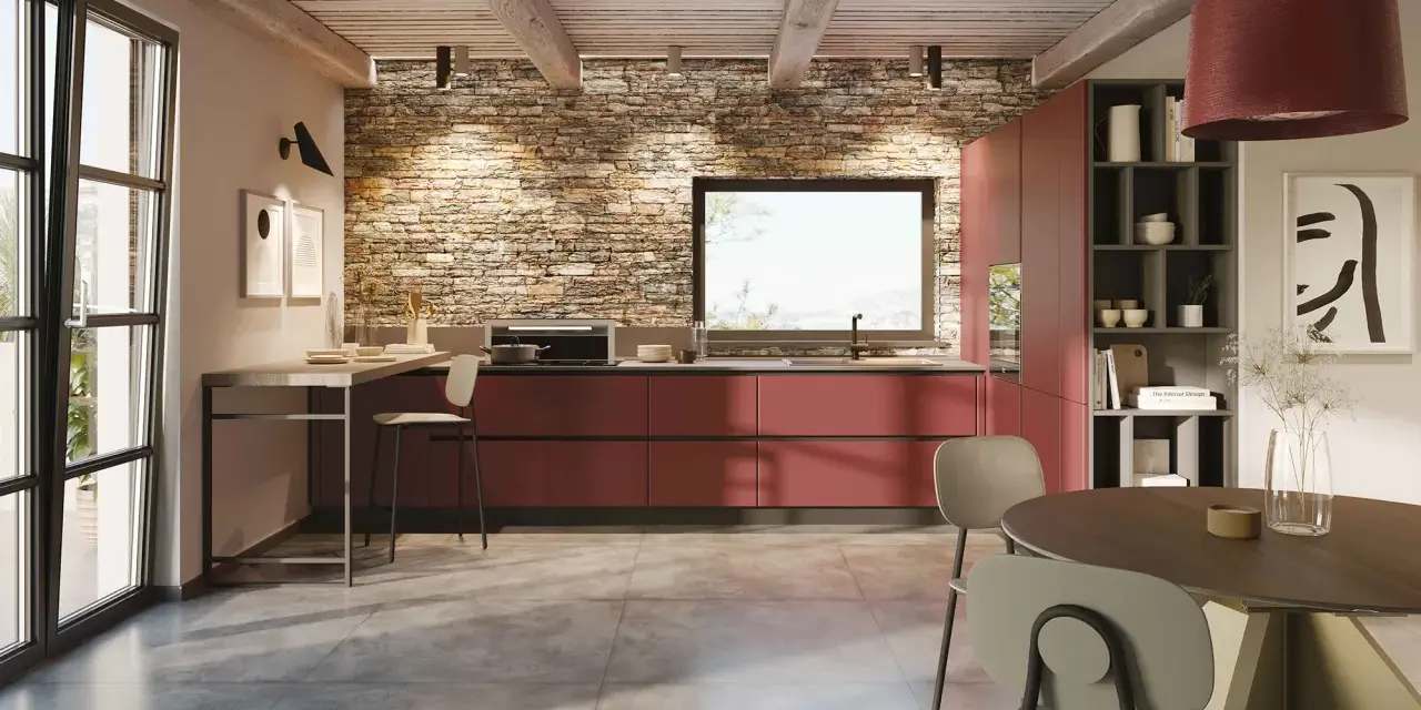 Cucina moderna con mobili rossi a vista, parete in pietra e un'isola che offre idee cucine ad angolo. Tavolo rotondo e sedie completano l'ambiente.