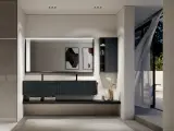 Elegante bagno moderno con mobile sospeso scuro, specchio illuminato e vista su un giardino esterno.