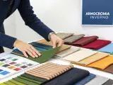 Mani che scelgono tessuti per una palette inverno. Campioni di stoffa in varie tonalità, dal verde al blu, dal beige all'arancione.