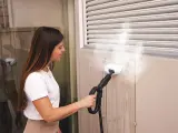 Donna usa un pulitore a vapore per pulire una superficie, come se stesse per pulire moquette con vaporetto.