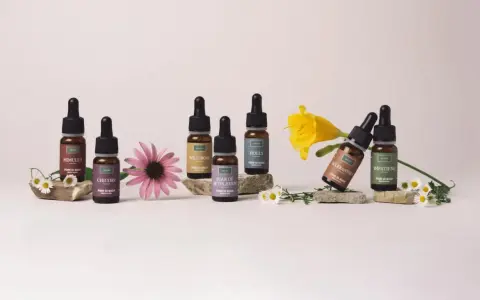 Flaconi di Fiori di Bach Rescue Remedy con Mimulus, Chicory, Wild Rose, Star of Bethlehem, Holly, Scleranthus e Impatiens, circondati da fiori.