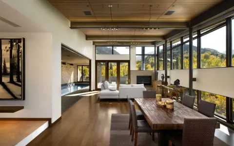 Ampio soggiorno con piscina interna, camino, tavolo da pranzo in legno e vista panoramica. Un perfetto test stile arredamento moderno.