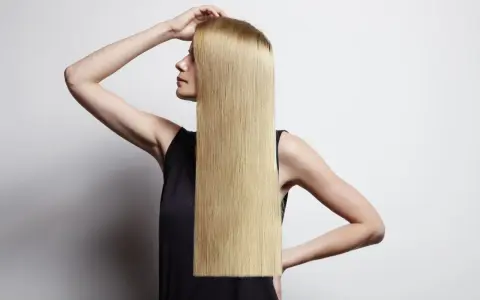 Donna con lunghi capelli biondi lisci, che mostra come lisciare i capelli a casa per un look impeccabile.