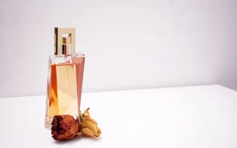 Elegante flacone di profumo dorato con rose secche, un'ispirazione su come scegliere un profumo che ti rappresenti.