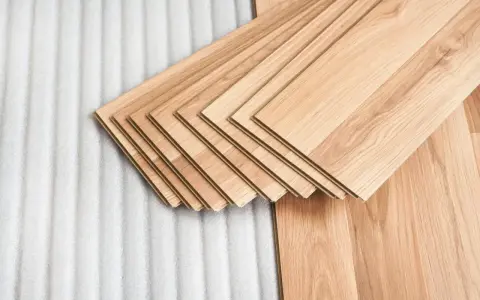 Assortimento di listoni di legno betulla colore chiaro, pronti per essere posati su un tappeto protettivo bianco.