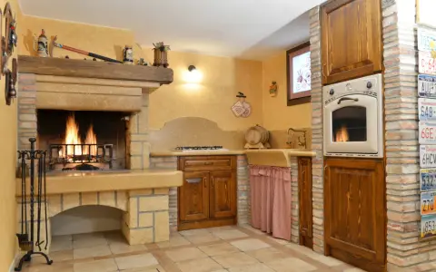 Accoglienti cucine di campagna con camino acceso, mobili in legno scuro e dettagli rustici. Un angolo cottura funzionale e un'atmosfera calda e invitante.