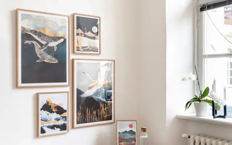 Un modo originale per appendere quadri: balene, paesaggi desertici, montagne e gru in volo decorano una parete chiara, creando un'atmosfera artistica.