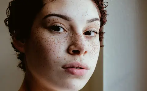 Primo piano di un volto con lentiggini naturali, un esempio di come fare le lentiggini in modo autentico.