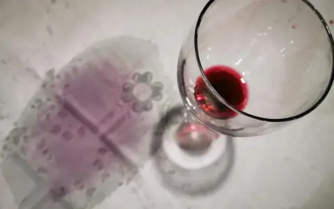 Un bicchiere di vino rosso rovesciato ha lasciato delle macchie sul tovagliolo, creando un'atmosfera di festa finita.