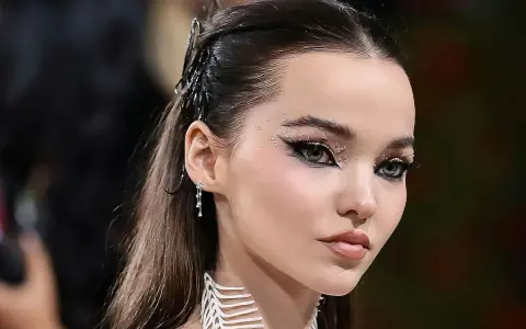 Occhi da sirena scintillanti con strass e eyeliner drammatico, capelli raccolti con accessori metallici.