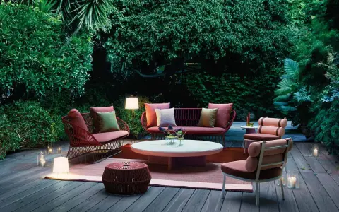 Un terrazzo accogliente con mobili da esterno color corallo e illuminazione soffusa, ideale per godersi la sera.